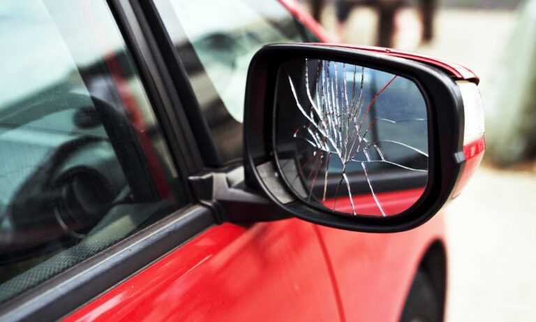 cracked side mirror on red car needing Houston auto glass repair